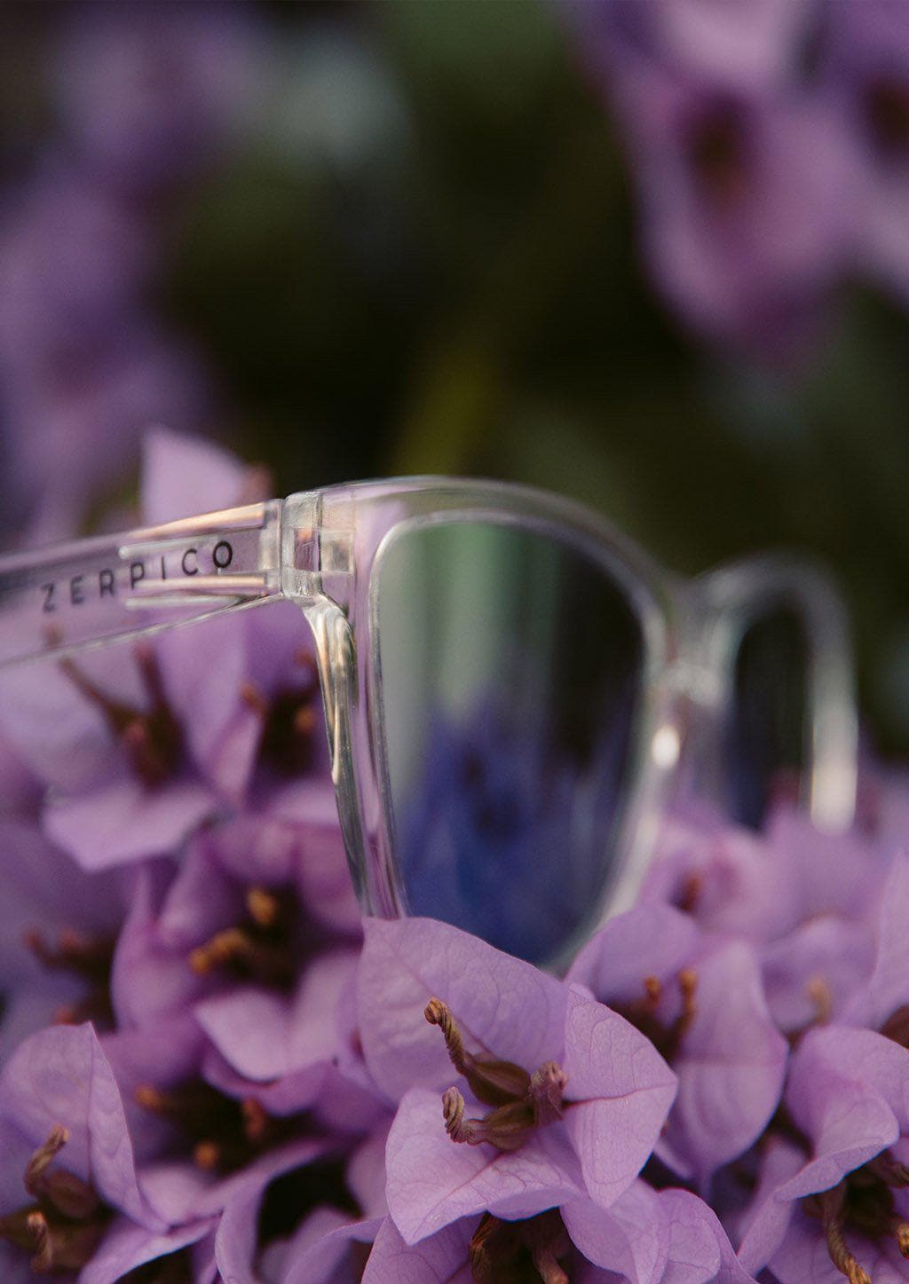 Our Mood V2 is an improved version of our last wayfarers. Plastic body for great quality and durabilty. This is Lucid with transparent frame and purple mirror lenses. Lifestyle shoot outside.