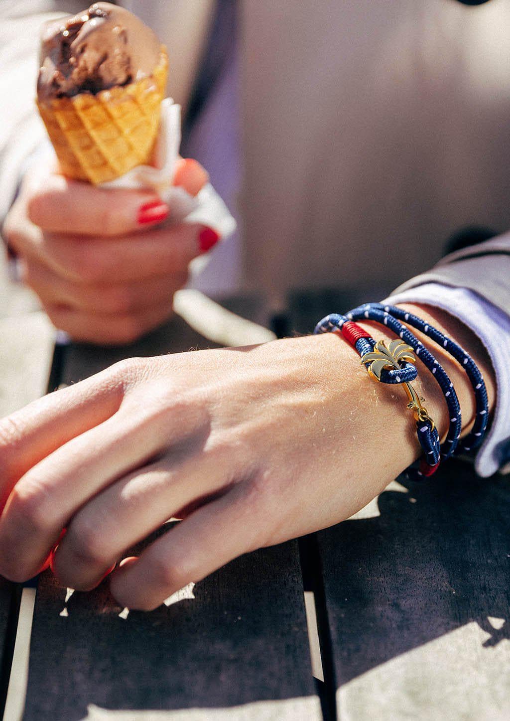 Seven Seas - Triple - Season two Palm anchor bracelet with blue and white nylon band. Female model holding ice cream.