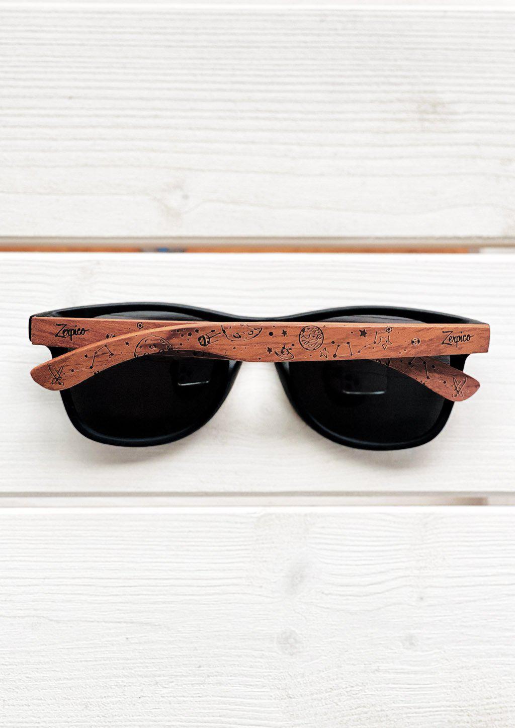 Our engraved sunglasses with motive from the stars and space. Outside on a park bench.