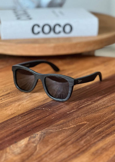 Our handmade wayfarer wooden sunglasses called Onyx Edge. Photo taken one a wooden table.