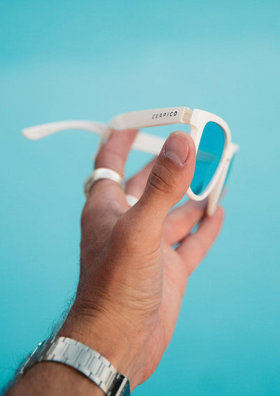 Our Mood V2 is an improved version of our last wayfarers. Plastic body for great quality and durabilty. This is Husky with white frame and blue lenses. Lifestyle photo outside.