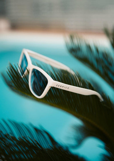 Our Mood V2 is an improved version of our last wayfarers. Plastic body for great quality and durabilty. This is Ace with white frame and black lenses. Lifestyle photo outside beside a pool.