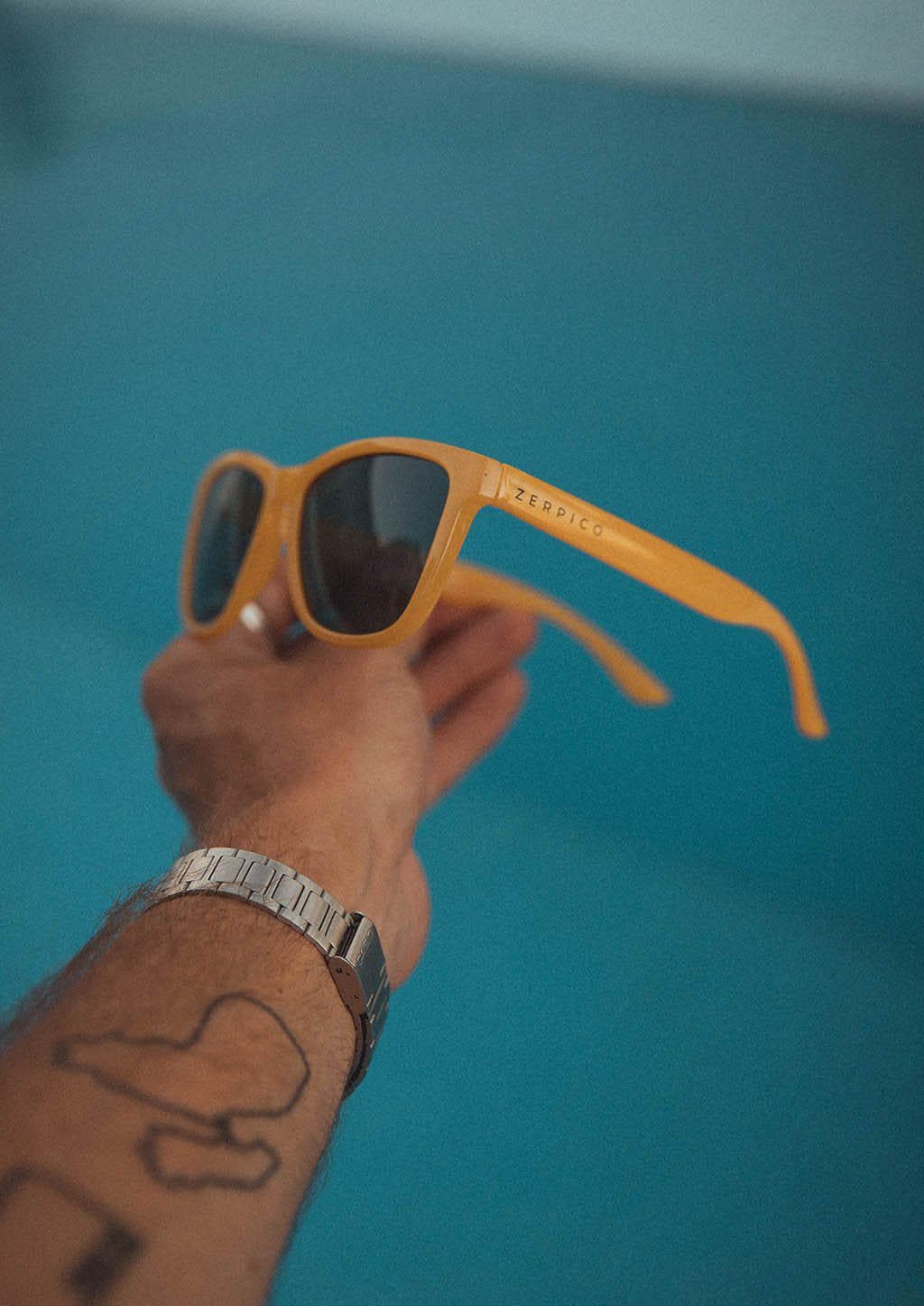 Our Mood V2 is an improved version of our last wayfarers. Plastic body for great quality and durabilty. This is Lemon with yellow frame and green lenses.  Lifestyle photo by the pool.