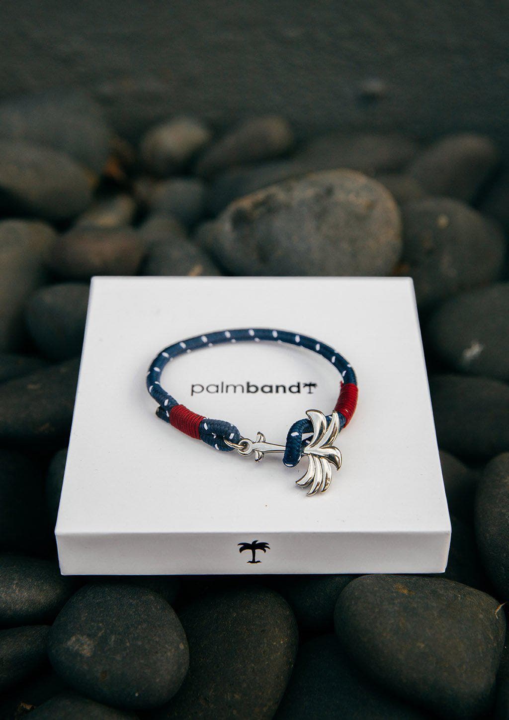 Voyager - Single - Season two Palm anchor bracelet with blue and red nylon band. Lying on box.