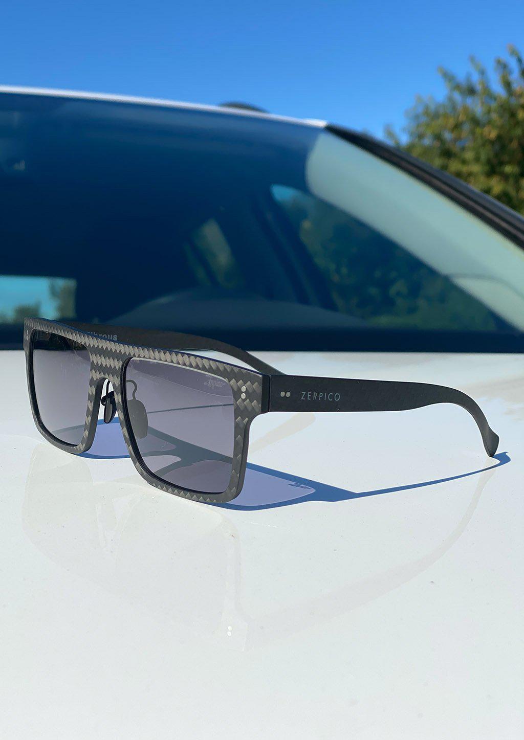 Our Anti Blue Light Square version of our Fibrous Carbon Fiber glasses. Perfect for gamers. Also turns dark outside. Photo showing the lenses turning darker.
