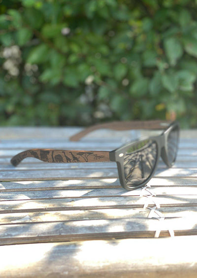 Engraved wooden sunglasses Inspired by the open plains and animals of the African savanna. Close up outside in the Swedish summer.