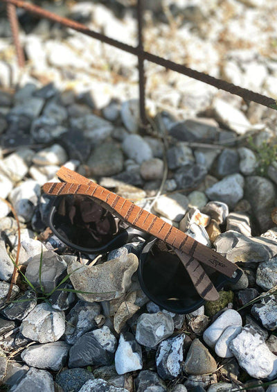 Engraved wooden sunglasses inspired by the untamed tigers and lions. Photo taken outside in the wild.