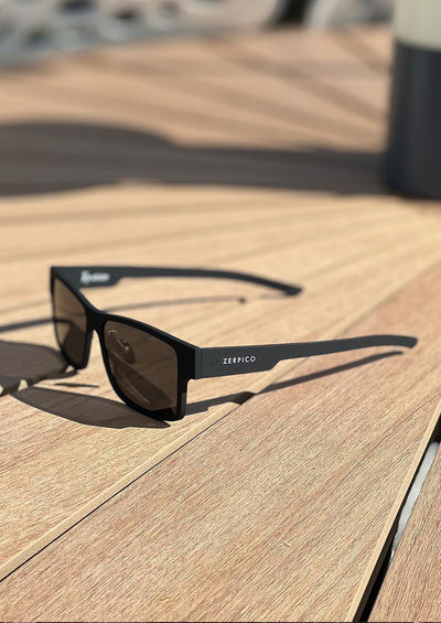 ReVision Square - Eco-Friendly Recyclable Paper Sunglasses with our black frame and black lenses outside in the sun.